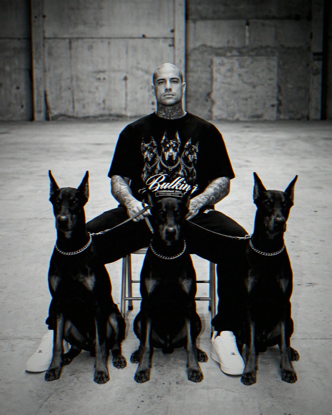 Atleta sentado entre três dobermans